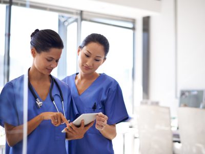 Shot of two female nurses using a tablet to review medical records